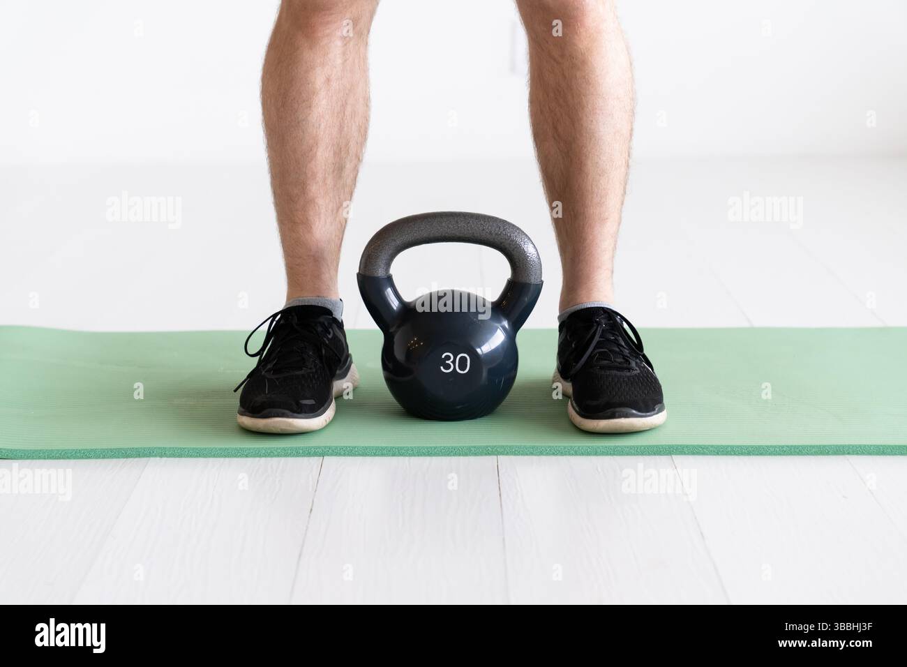 Kettlebell sitzt auf einer Yoga-Matte neben einem Mann Stockfoto