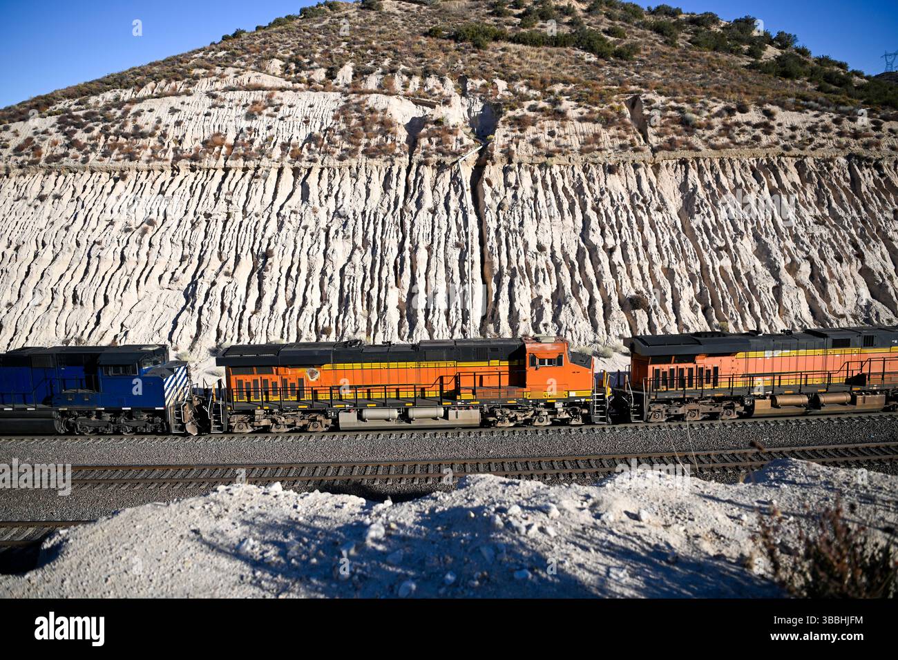 Lokomotiven, die unten auf der Eisenbahn durch eine trockene Schlucht fahren Stockfoto