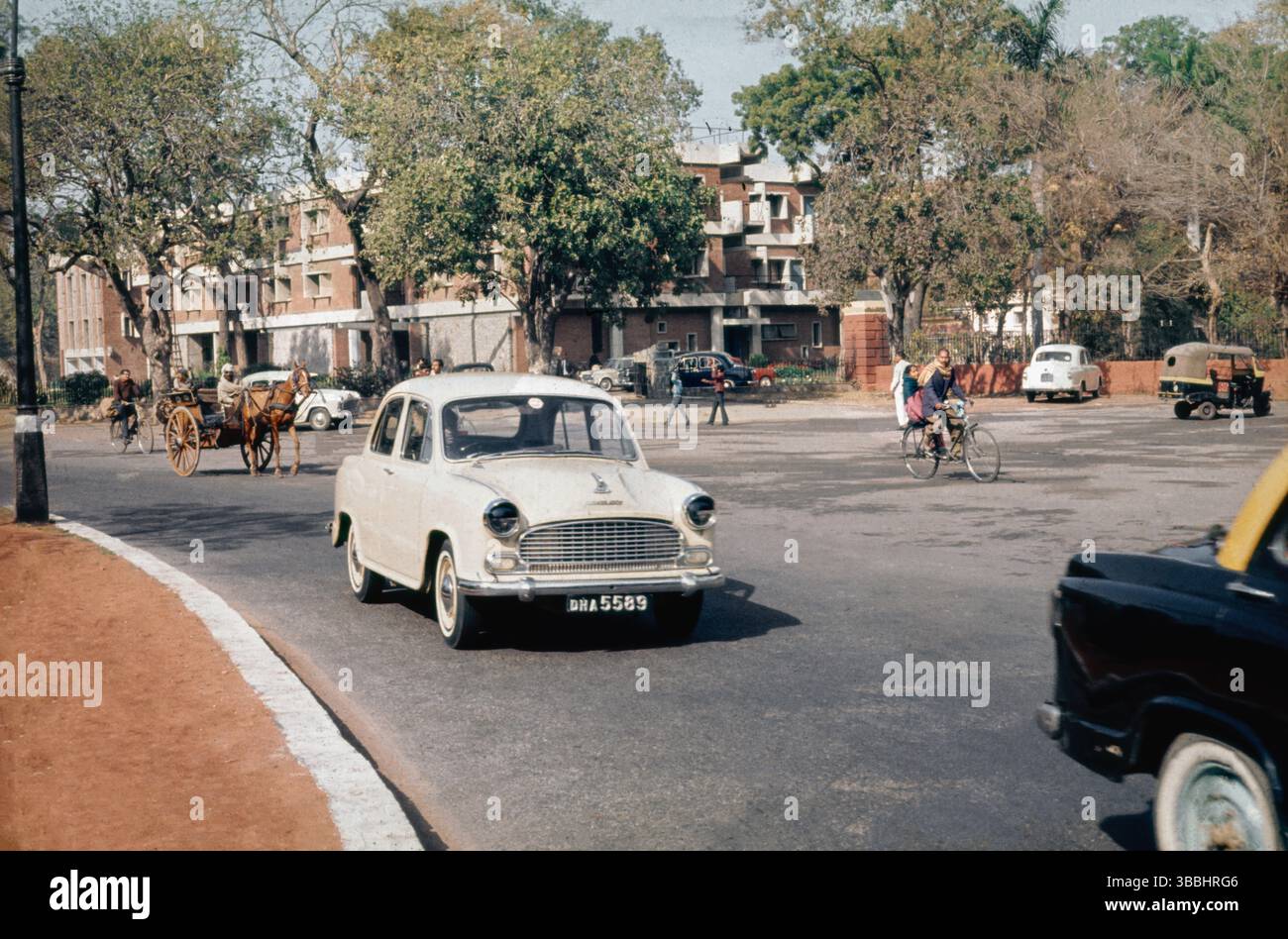 Vintage-Straßenszene in Indien mit einem Hindustan Ambassador-Auto, indisches Straßenleben aus den 1950er und 1950er Jahren mit verschiedenen Verkehrsmitteln Stockfoto