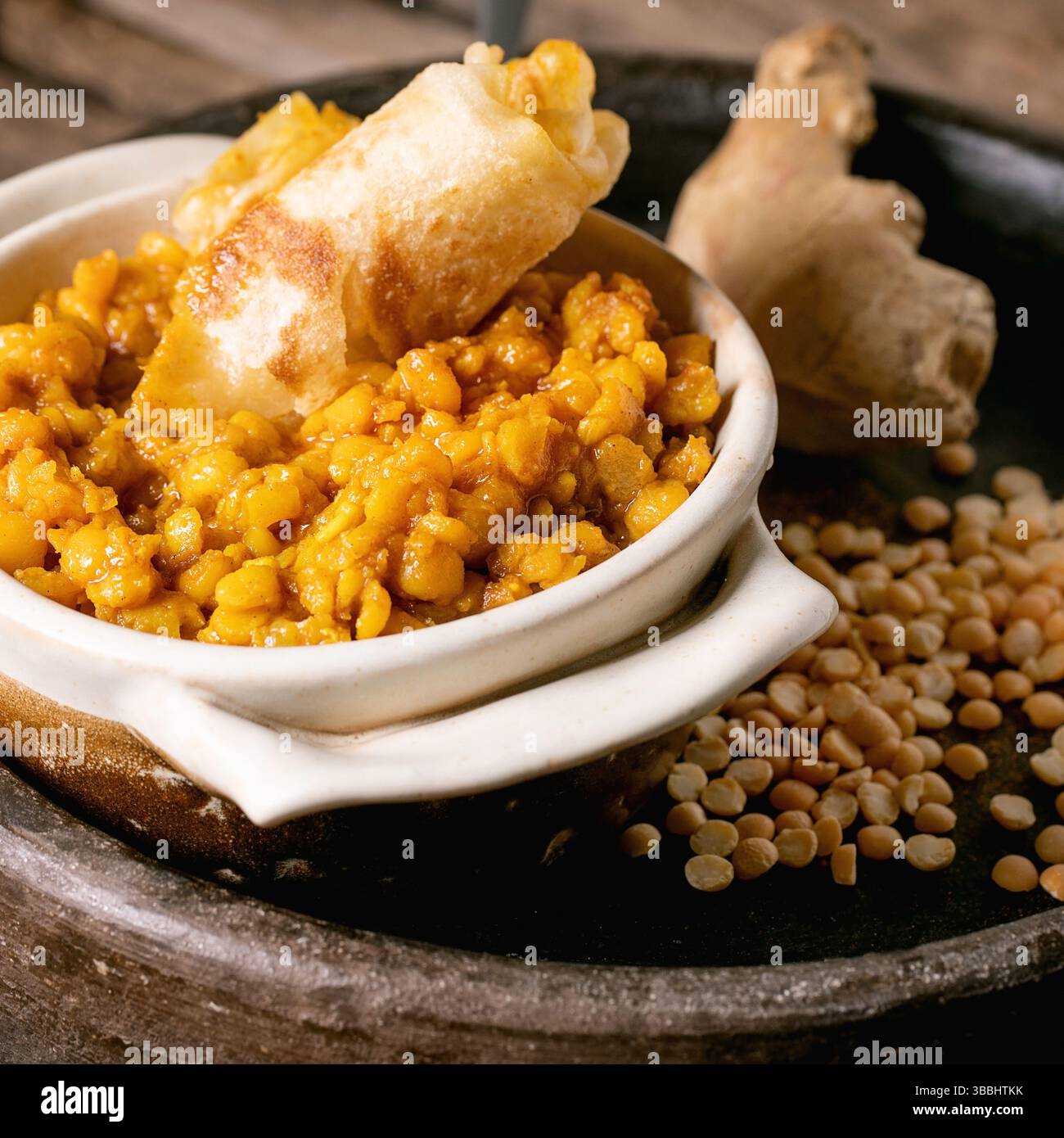 Dhal mit Roti-Brot. Traditionelles indisches vegetarisches Yellow-Pea-Essen mit Roti-Fladenbrot, serviert mit Zitrone in einer Keramikschale auf einem alten Holztisch. Stockfoto