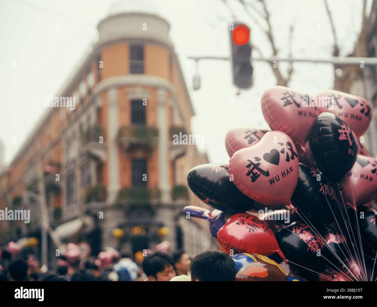 Herzförmige „Wuhan Love“-Ballons inmitten von Menschenmassen und kolonialer Architektur in einer Wuhan Street, Hubei, China Stockfoto