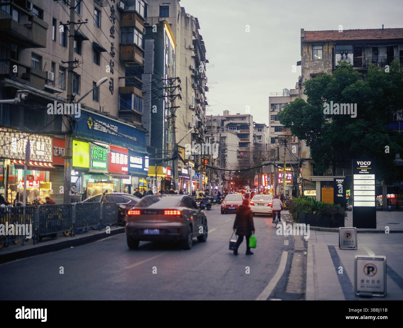 Wuhan Urban Street Scene mit abendlichem Verkehr und Fußgängerüberquerung, Hubei, China Stockfoto