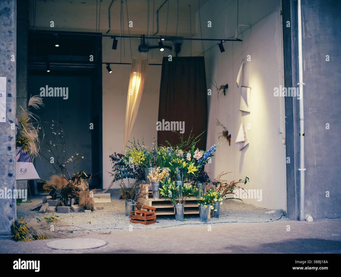 Industriell-schicke Blumenpräsentation in einer umgestalteten Lagergalerie Stockfoto