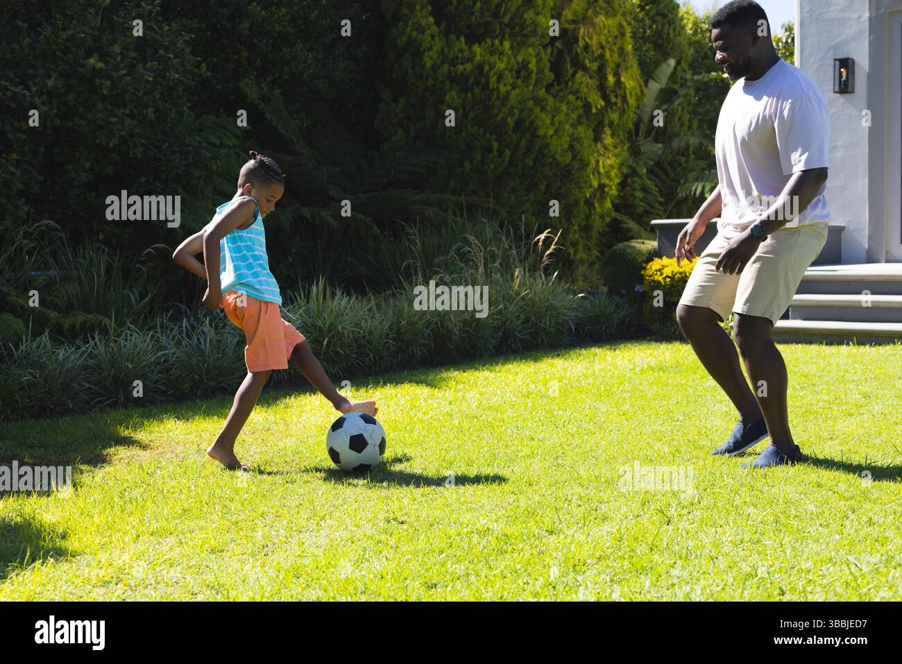 Afroamerikaner Vater und Sohn in Sportbekleidung auf dem Garten spielen, mit Fußball Stockfoto