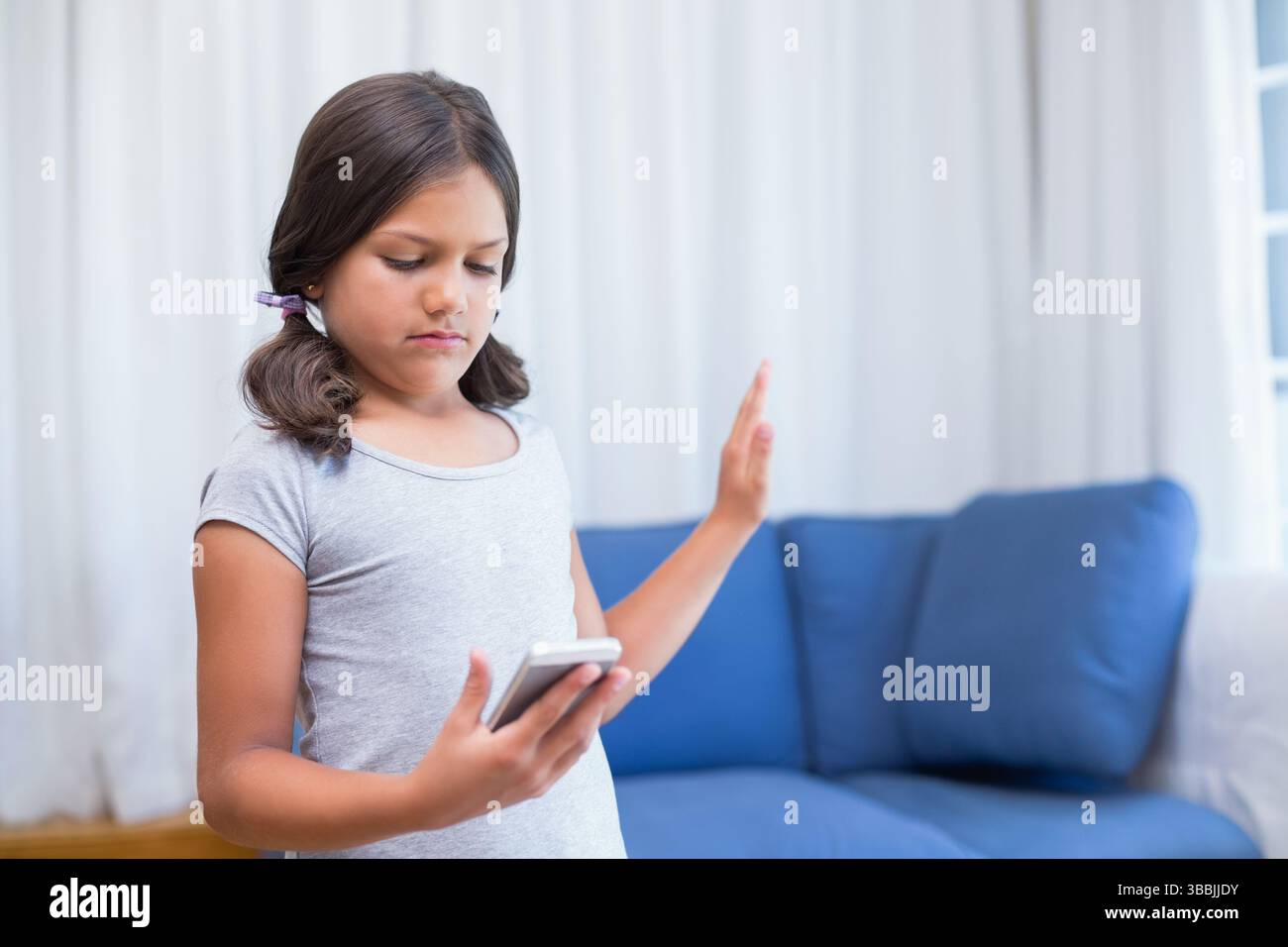 Smartphone halten und Stop Geste Mädchen Kind im Wohnzimmer, Kopierraum Stockfoto