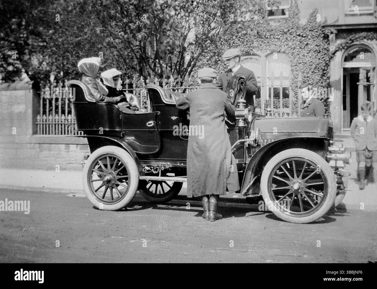 Aus einem originalen Albumenbild, etwas größer als ein Schnappschuss und datiert um die frühen 1900er Jahre: Zwei Herren stehen neben einem Auto mit zwei Damen auf den Rücksitzen des Rolls-Royce 10 ps Autos von 1905. Aus einem viktorianischen und edwardianischen Scrapbook, das scheinbar von einer unbenannten Person zusammengestellt wurde. Stockfoto