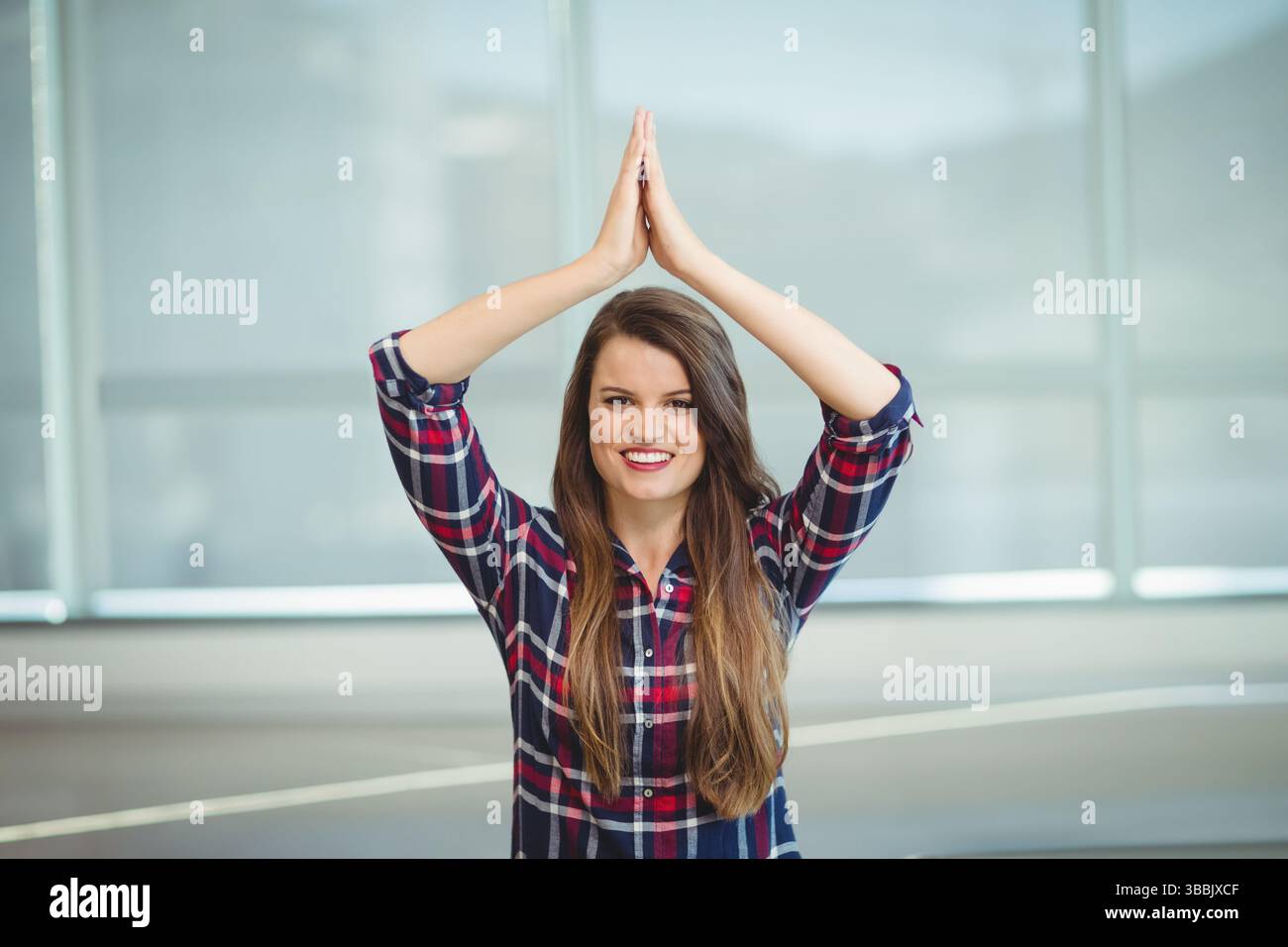 Stehende Frau, die durch hohe Fenster im modernen Innenraum blickt und architektonische Linien hervorhebt Stockfoto