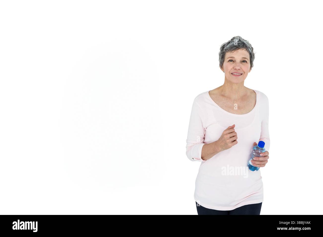 Ältere Frau, die eine klare Plastikwasserflasche mit blauer Kappe im Studio hält, Kopierraum Stockfoto