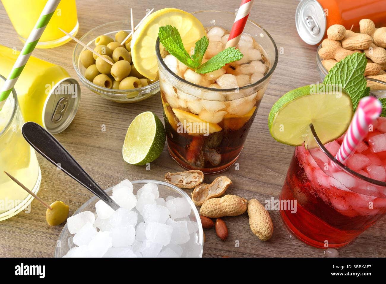 Festlicher Hintergrund mit Gläsern mit erfrischenden Getränken und Behältern mit Snacks auf einem Holztisch mit Gläsern und Früchten. Erhöhte Aussicht. Stockfoto