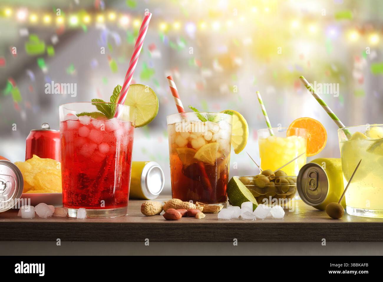 Hintergrund mit einem Tisch mit Gläsern erfrischender Getränke, Snacks und Dosen mit festlichem Hintergrund in einem Raum mit farbigen Lichtern und Konfetti. Vor Stockfoto