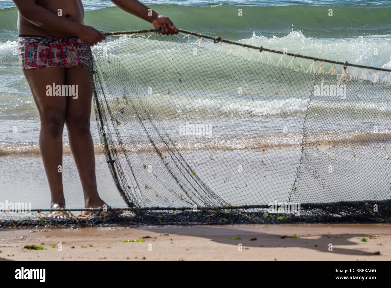 Der halbe Körper eines nicht identifizierten Fischers, der ein Fischernetz zieht. Fisch und Meeresfrüchte, Hobby. Brasilien Stockfoto