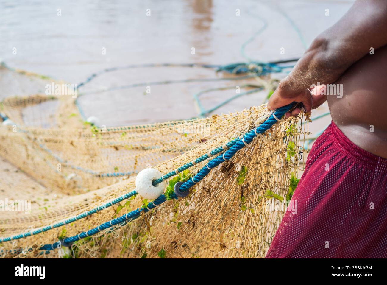 Der halbe Körper eines nicht identifizierten Fischers, der ein Fischernetz zieht. Fisch und Meeresfrüchte, Hobby. Brasilien Stockfoto