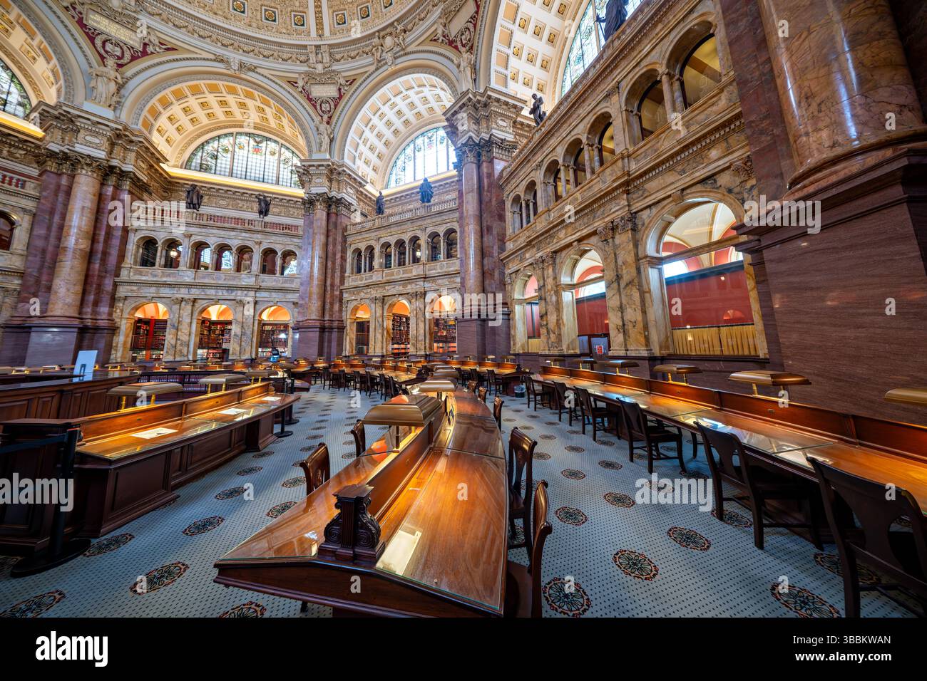 WASHINGTON DC – der Hauptlesungsraum des Thomas Jefferson Building in der Library of Congress ist einer der prächtigsten öffentlichen Räume Amerikas. Dieser achteckige Raum wurde 1897 fertiggestellt und erhebt sich 160 Meter zu einer kunstvollen Kuppel mit Edwin Howland Blashfields Gemälde „menschliches Verständnis“, umgeben von allegorischen Figuren, die Länder repräsentieren, die zum menschlichen Wissen beigetragen haben. Der Lesesaal verfügt über massive Säulen aus rotem Marmor mit vergoldeten korinthischen Kapitellen, Bronzestatuen, die Wissensfelder darstellen, und drei Reihen von Bücherstapeln, die den zentralen Raum umkreisen. Entwickelt Stockfoto