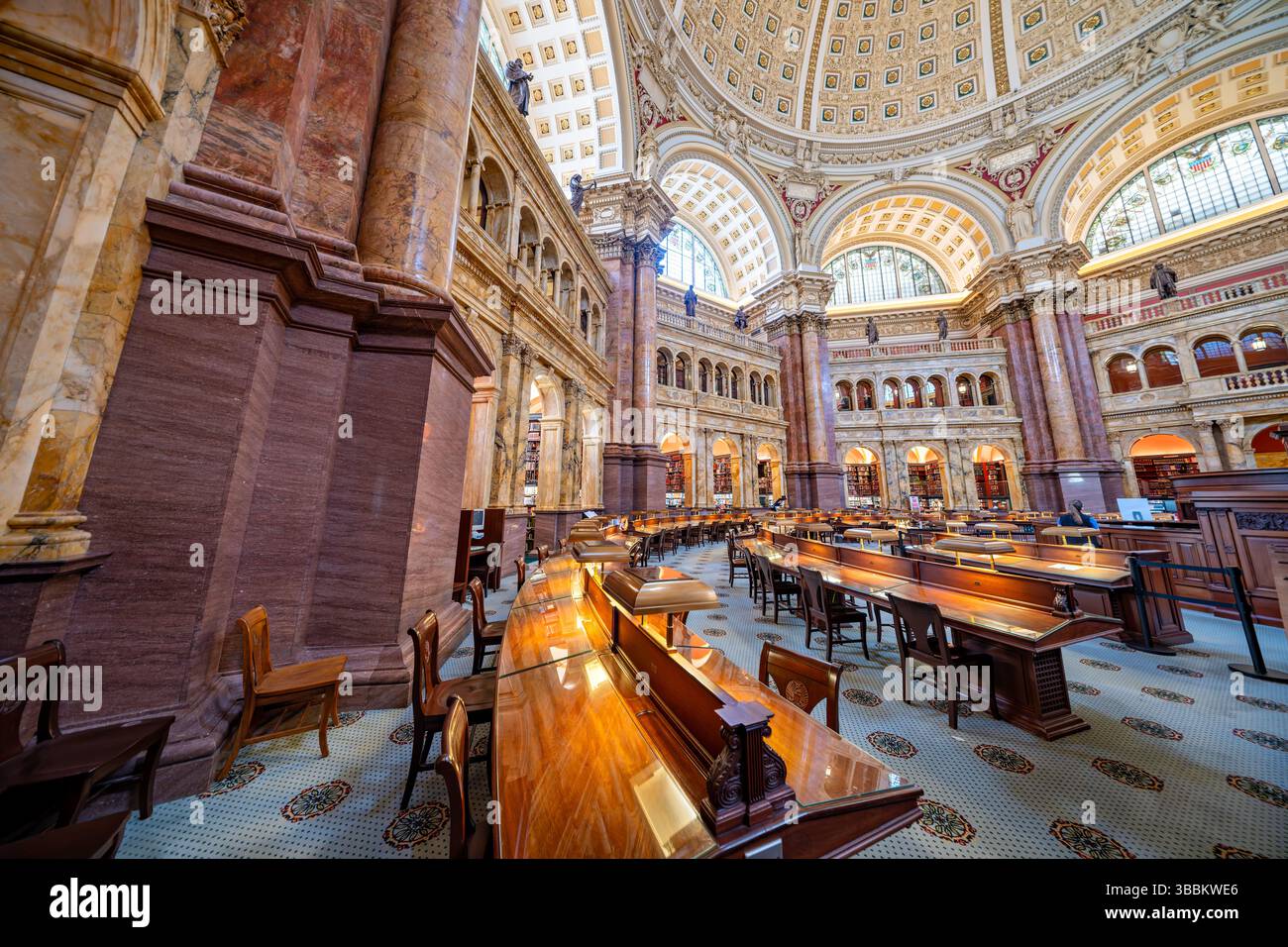 WASHINGTON DC – der Hauptlesungsraum des Thomas Jefferson Building in der Library of Congress ist einer der prächtigsten öffentlichen Räume Amerikas. Dieser achteckige Raum wurde 1897 fertiggestellt und erhebt sich 160 Meter zu einer kunstvollen Kuppel mit Edwin Howland Blashfields Gemälde „menschliches Verständnis“, umgeben von allegorischen Figuren, die Länder repräsentieren, die zum menschlichen Wissen beigetragen haben. Der Lesesaal verfügt über massive Säulen aus rotem Marmor mit vergoldeten korinthischen Kapitellen, Bronzestatuen, die Wissensfelder darstellen, und drei Reihen von Bücherstapeln, die den zentralen Raum umkreisen. Entwickelt Stockfoto