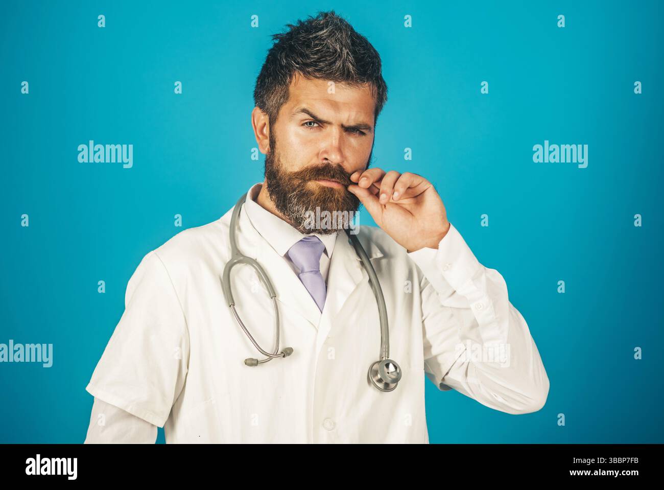 Ernsthafter Arzt mit Bart und Schnurrbart im medizinischen Kleid mit Stethoskop im Krankenhaus. Gesundheitswesen, Klinik, Medizin, Behandlung und medizinisches Personal Stockfoto