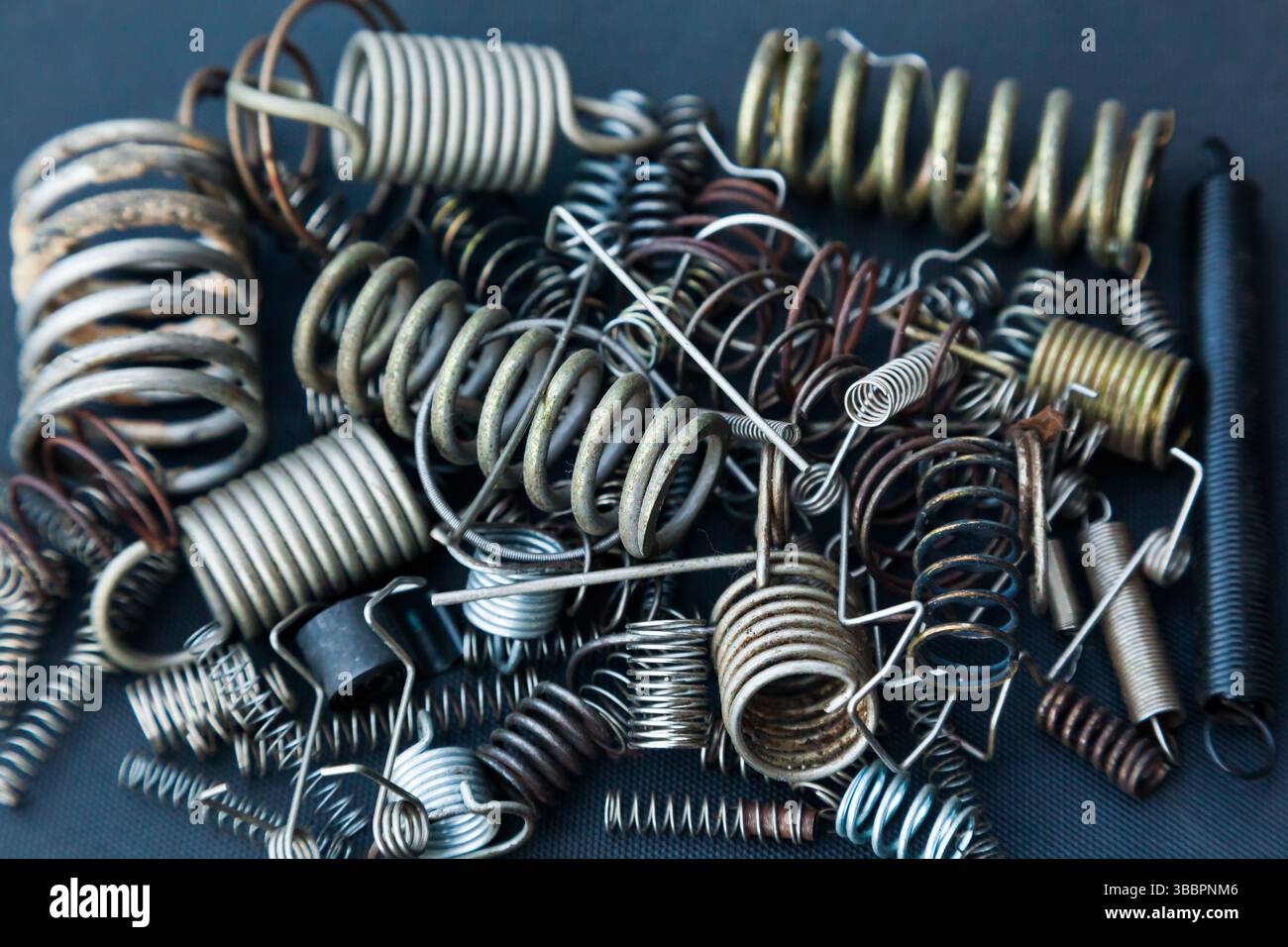 Viele kleine Federn unterschiedlicher Größe liegen auf einem Haufen vor schwarzem Hintergrund. Stockfoto