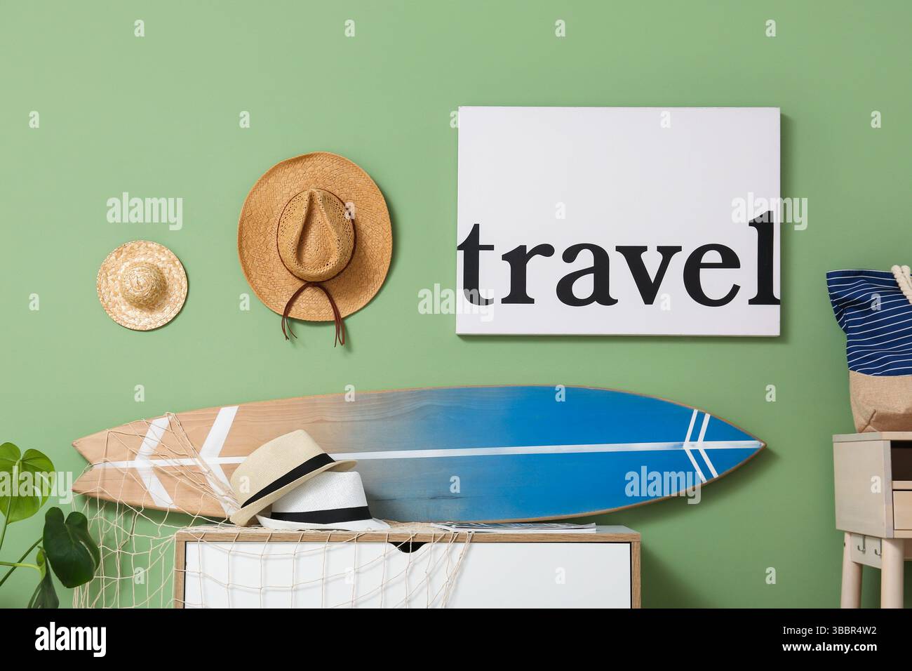 Poster mit WORTREISEN, Hüten und Surfbrett auf Kommode in stilvollem Zimmer, Nahaufnahme Stockfoto