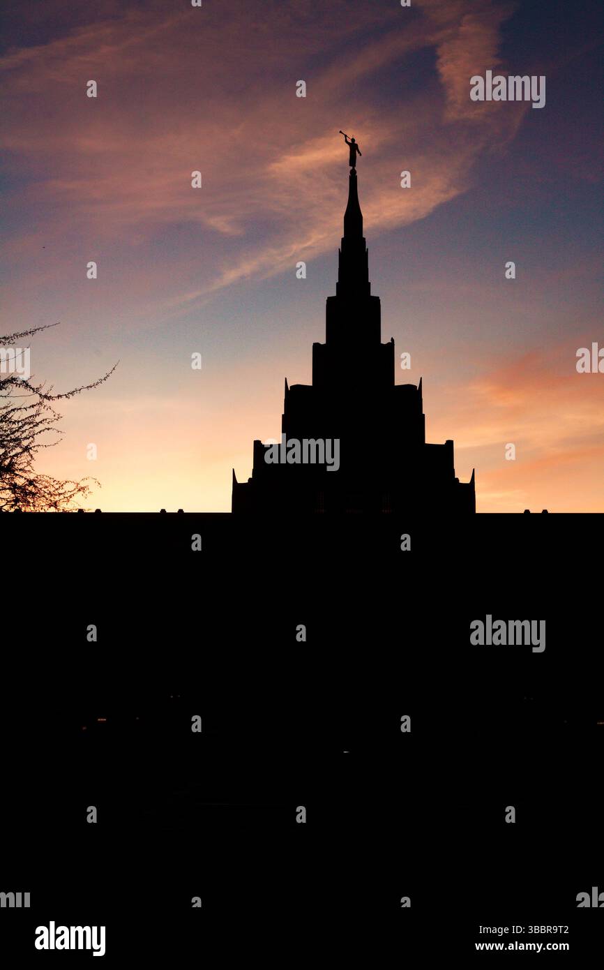 Silhouette eines majestätischen LDS-Tempels bei Sonnenuntergang mit dem Engel Moroni auf der Spitze des Turms unter einem lebendigen Abendhimmel – symbolisiert Frieden und Glauben. Stockfoto