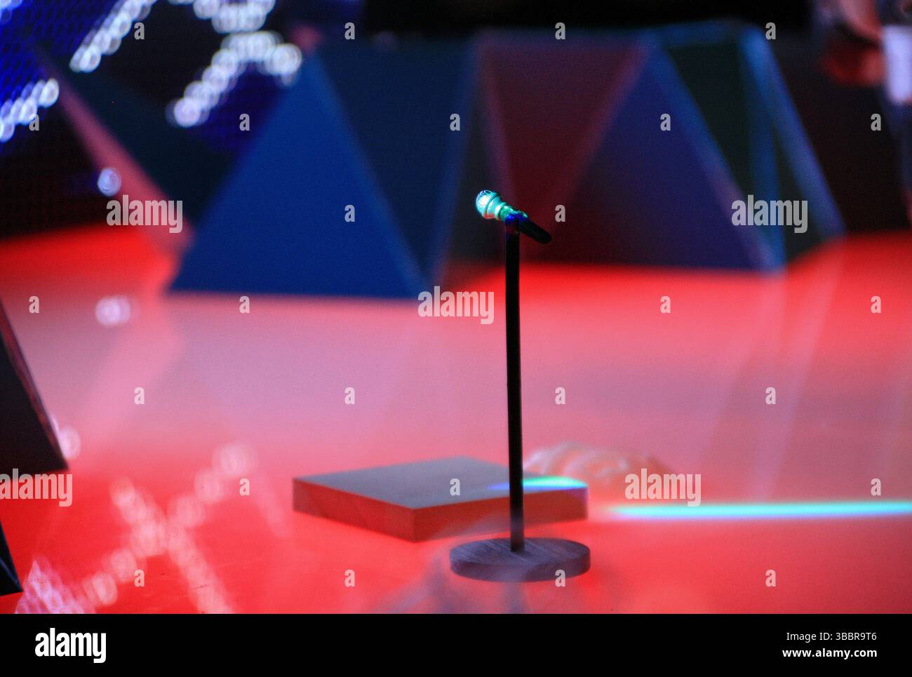 Leere Bühne mit leuchtendem Mikrofon unter dramatischer Beleuchtung, die die Vorfreude und Energie einer bevorstehenden Live-Performance oder eines Musikereignisses einfängt. Stockfoto