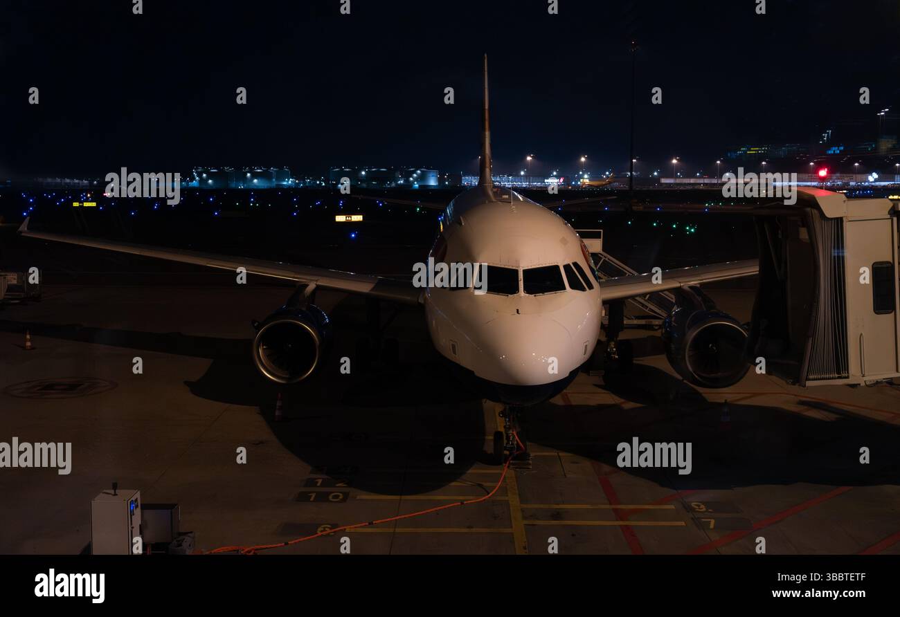 Vorderes Fahrwerk und Cockpit des Flugzeugs bei Nacht auf der Start- und Landebahn des Flughafens. Luft- und Raumfahrtindustrie. Stockfoto