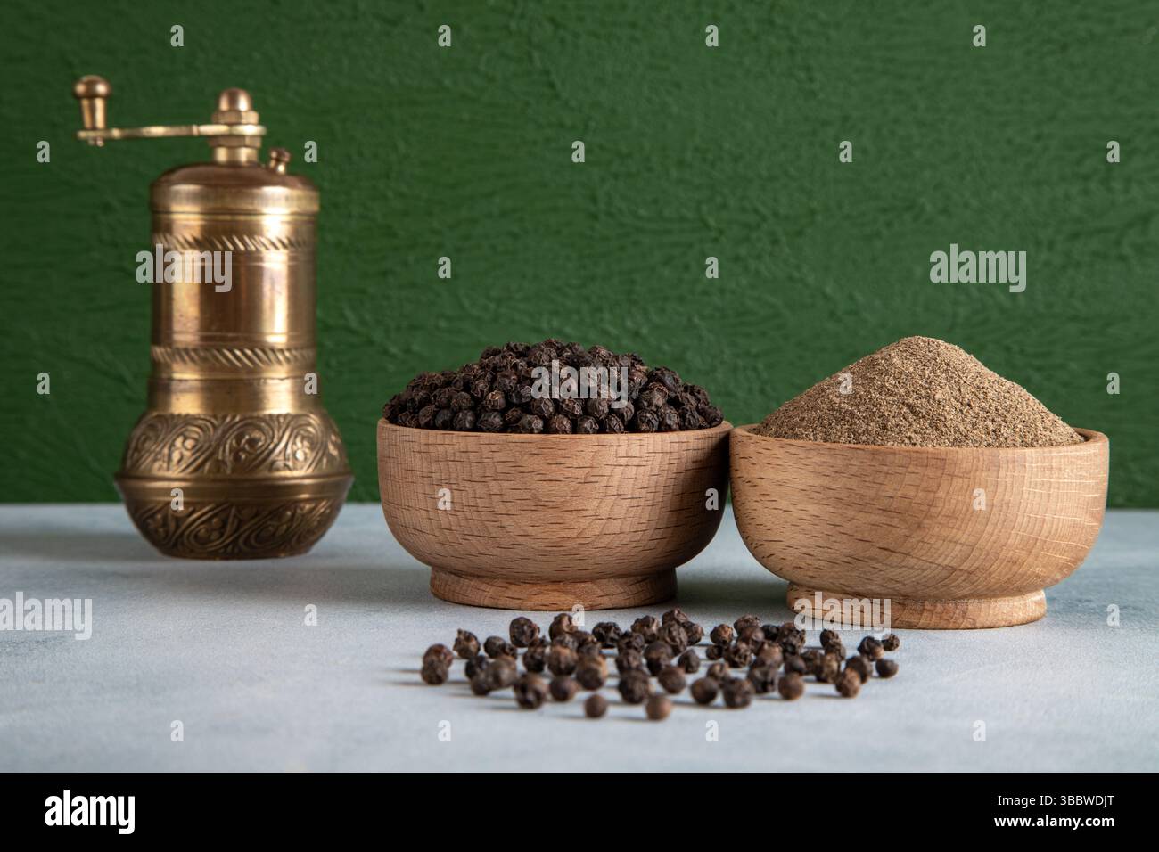 Schwarze Pfefferkörner, gemahlener schwarzer Pfeffer und Metallmahlmaschine Stockfoto