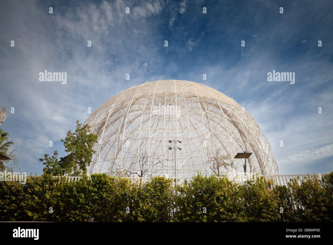 VALENCIA, SPANIEN - 13. OKTOBER 2024: Die riesige Gitterkuppelvoliere am Bioparc Valencia erhebt sich über üppigem Grün vor dem hellen mediterranen Himmel, ITS Stockfoto