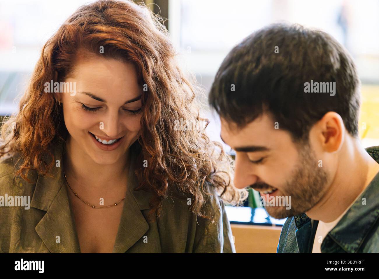 Junge Paare genießen einen entspannten Moment, während sie gemeinsam ein Menü in einem stilvollen Café-Interieur durchsuchen und dabei die Verbundenheit, Wärme und gemeinsame Genüsse hervorheben Stockfoto