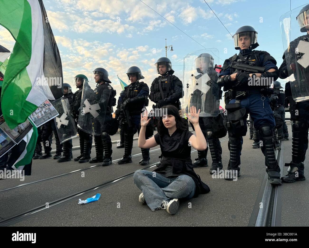 Basel, Schweiz. Mai 2025. Eine Frau sitzt vor einer Reihe von Polizeibeamten auf der Mittelrheinbrücke, die am Tag des großen Finales des 69. Eurovision Song Contests (ESC) eine propalästinensische Demonstration absperren und ihre Hände mit dem Schriftzug „Land Back“ hochhalten. Quelle: Aleksandra Bakmaz/dpa/Alamy Live News Stockfoto