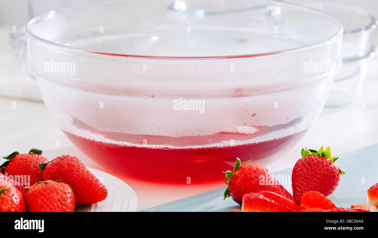Glasschale gefüllt mit frisch gemischtem Erdbeergelee auf der Theke. Stockfoto
