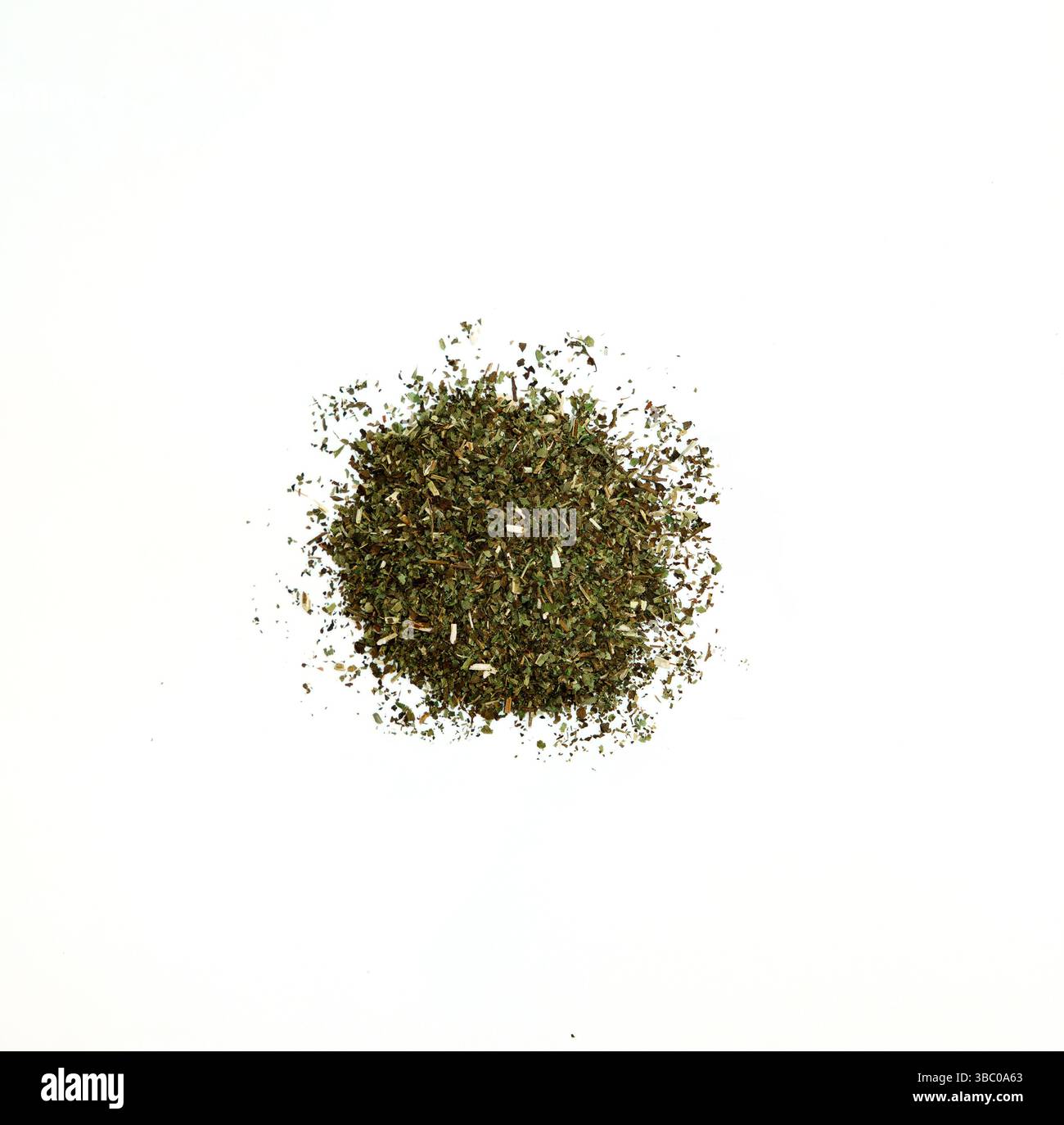 Ein kleiner Haufen getrockneter Melisa wird zentral vor einem stark weißen Hintergrund positioniert. Das Kraut ist lose zusammengefaßt, einige Fragmente sind verstreut Stockfoto
