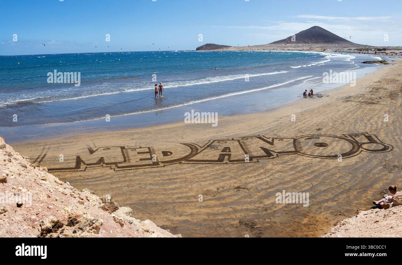 Große Buchstaben, die El Medano im Sand am Strand zeigen, mit montana roja im Hintergrund roten Berg Stockfoto