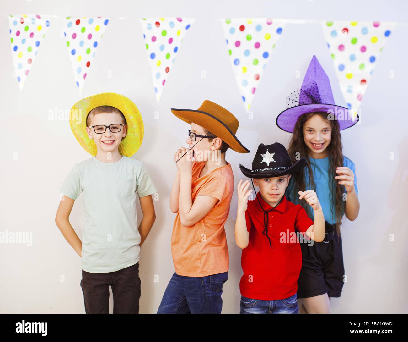 Fröhliche aufgeregte Kinder, die Spaß zusammen auf der Geburtstagsparty haben. Kinder in lustigen Hüten und Kostümen. Unterhaltung für Kinder und Freizeit Stockfoto