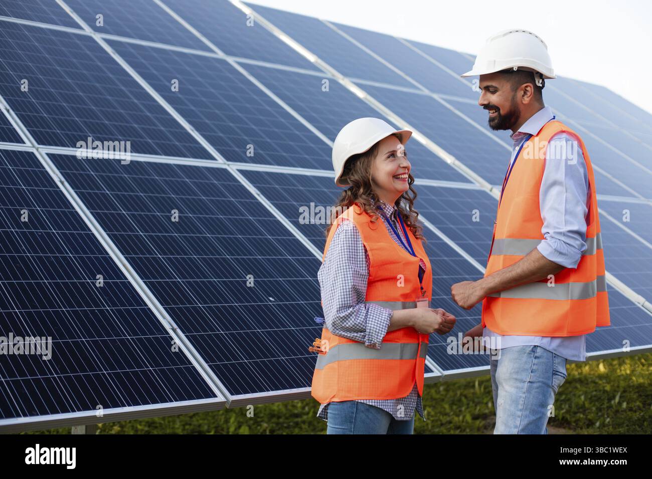 Zwei Ingenieure in Uniform stehen vor dem Hintergrund von Solarmodulen und diskutieren die Situation Stockfoto