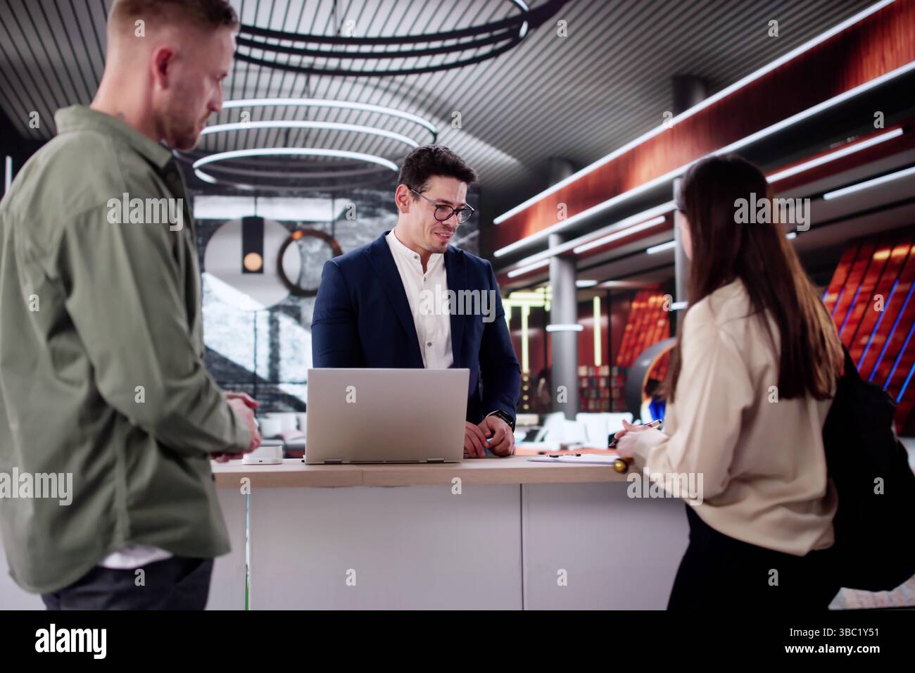Beim Einchecken an der Hotelrezeption trifft sich Ein Paar auf den Concierge. Stockfoto