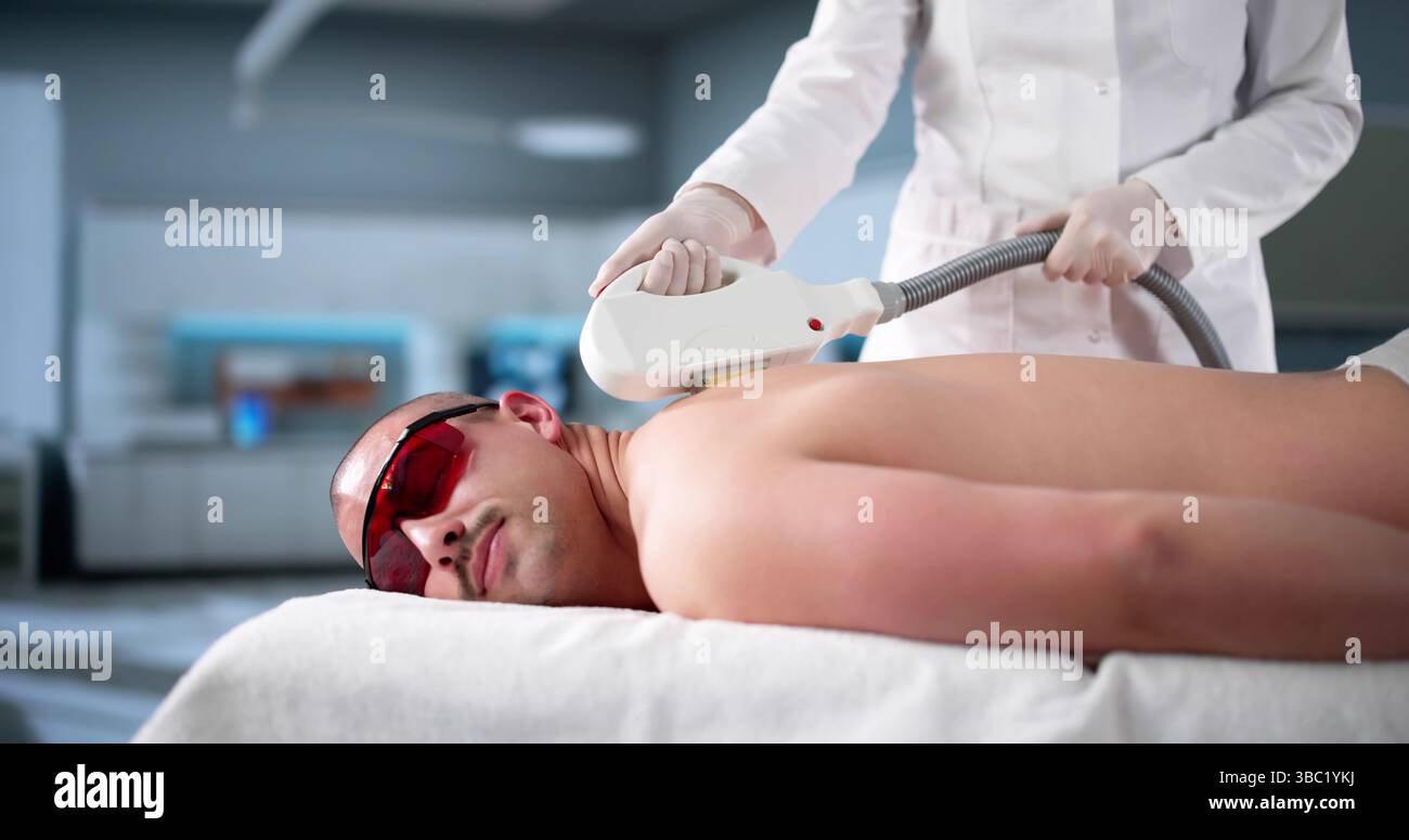 Männlicher Kosmetiker, der Laser-IPL-Haarentfernungsbehandlung unter Verwendung von Technologie anbietet Stockfoto