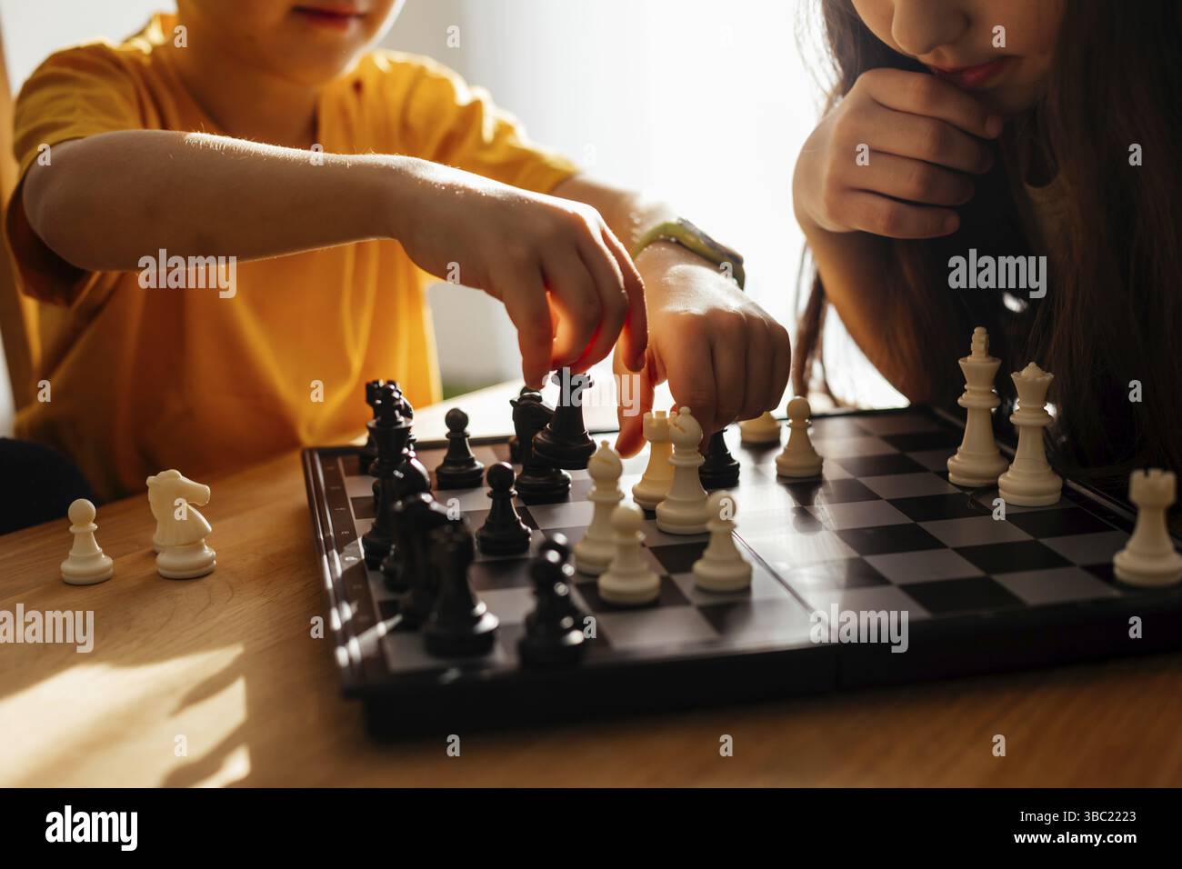 Großschach-Brett während des Spiels. Der Grundschuljunge bewegt Figuren auf einem Brett. Schwester und Bruder lernen strategische Planung während des Schachspiels Stockfoto