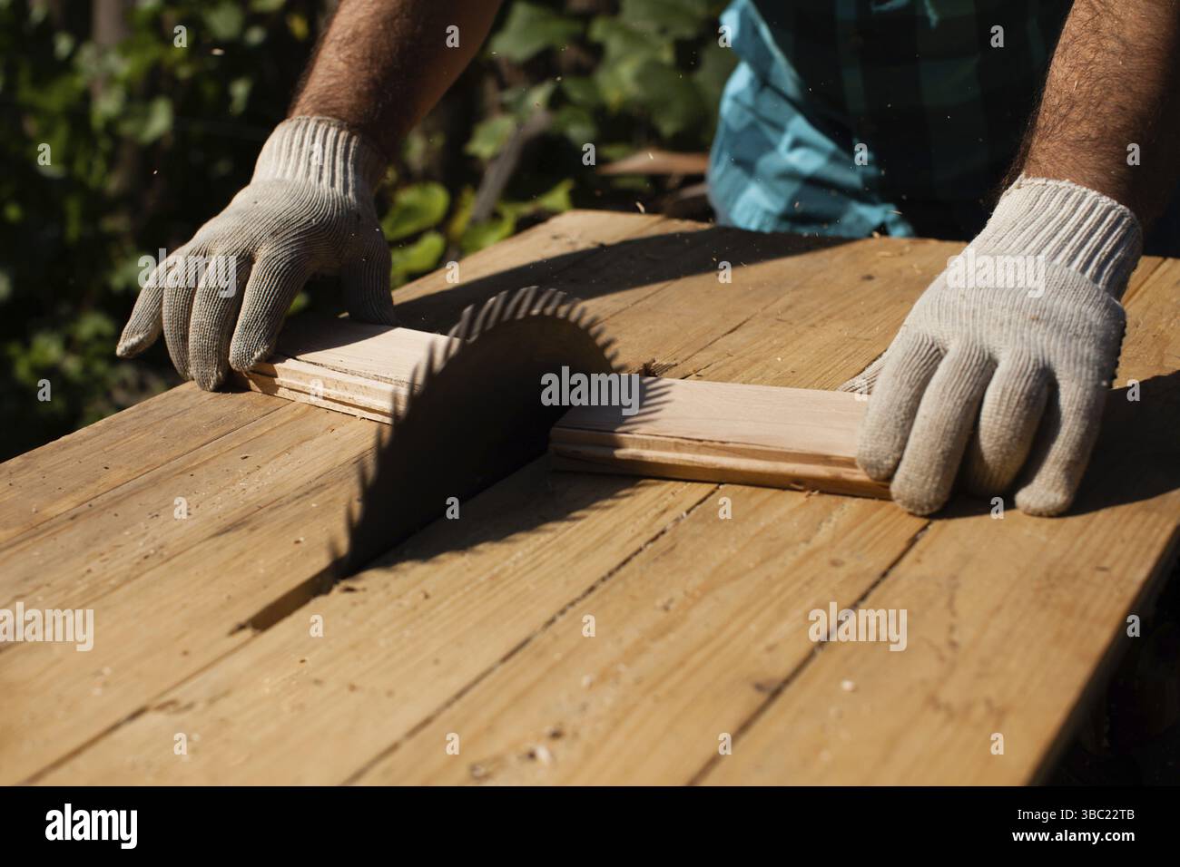 Hart arbeitender Holzarbeiter, der Holzbohlen schneidet, Fokus auf Säge Stockfoto