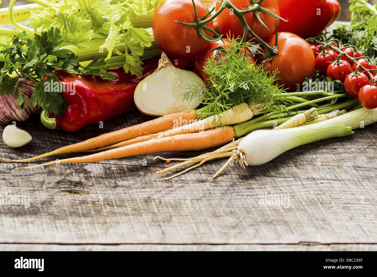 Eine Auswahl an frischem, frisch gepflücktem Gemüse. Ökologischer Landbau. Karotten, Sellerie, Tomaten und Kopfsalat auf Holzfläche. Speicherplatz kopieren Stockfoto