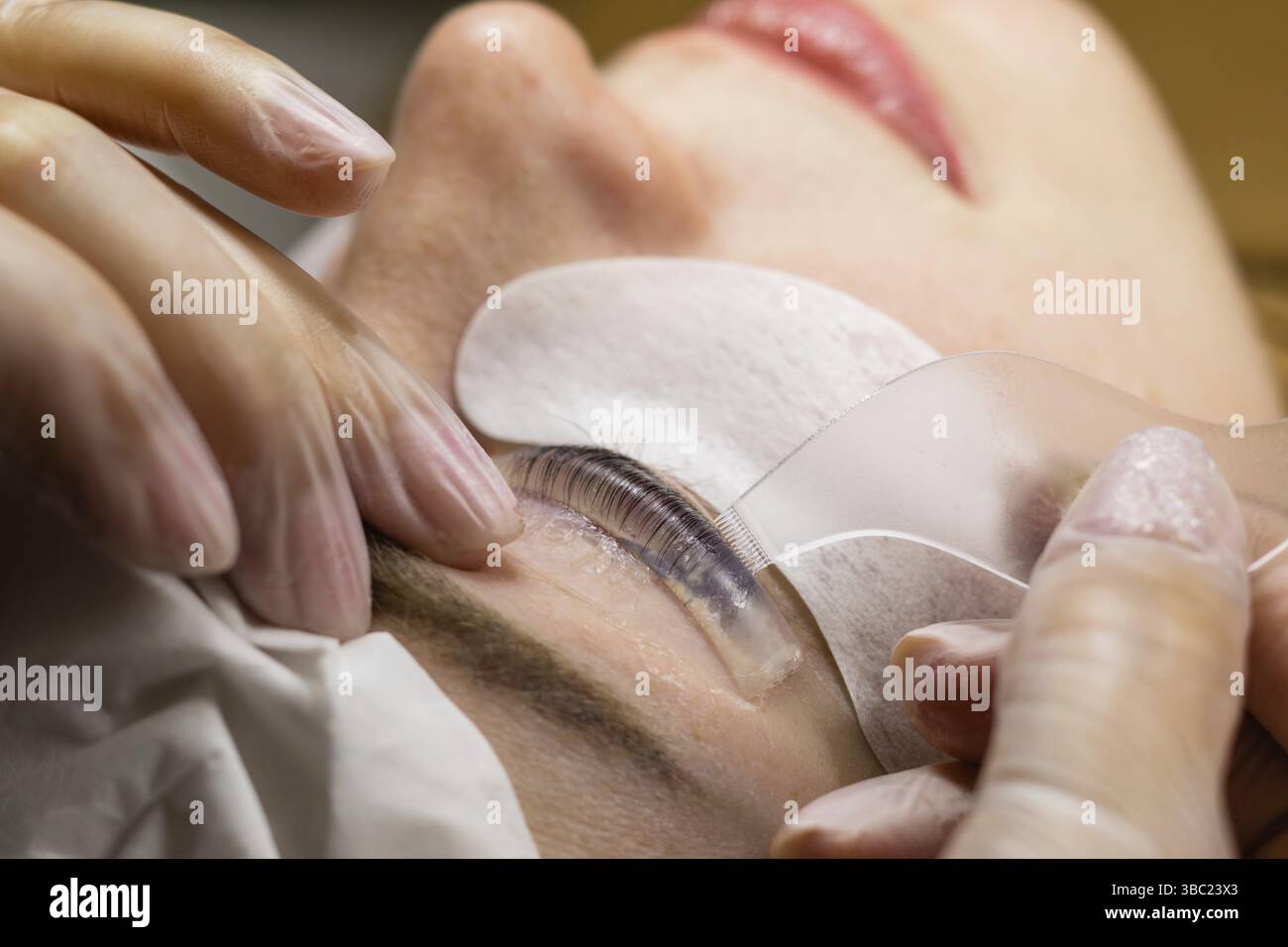 Weibliches Gesicht unter Eingriff der Wimpern Laminierung im Schönheitssalon, Nahaufnahme Stockfoto