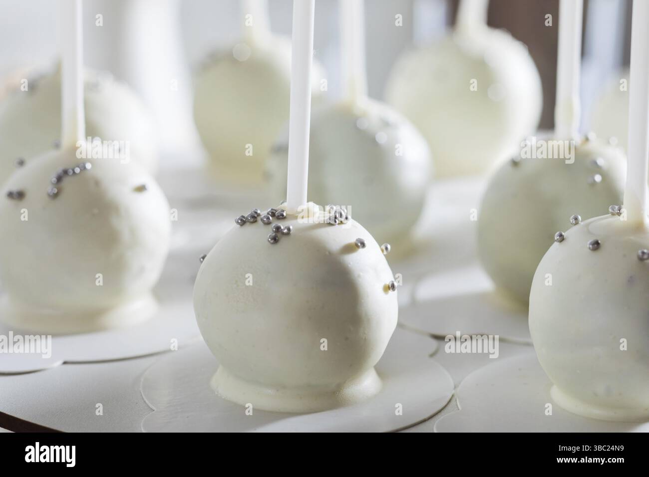 Die Nahaufnahme von Kuchen mit weißer Sahne. Die kugelförmigen Kuchen mit einem Stock auf einem Ständer Stockfoto