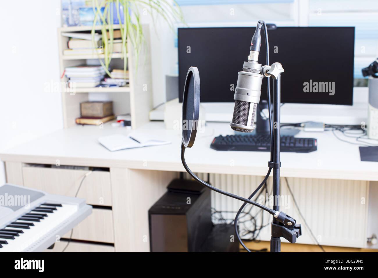 Das professionelle Kondensatormikrofon auf dem Hintergrund verschiedener Geräte zur Aufnahme und Verarbeitung von Musik Stockfoto