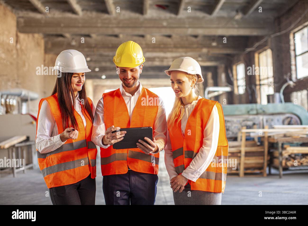 Team junger Bauarbeiter, das Projektdetails mit dem Vorgesetzten bespricht. Professionelle Leute mit Helmen Stockfoto