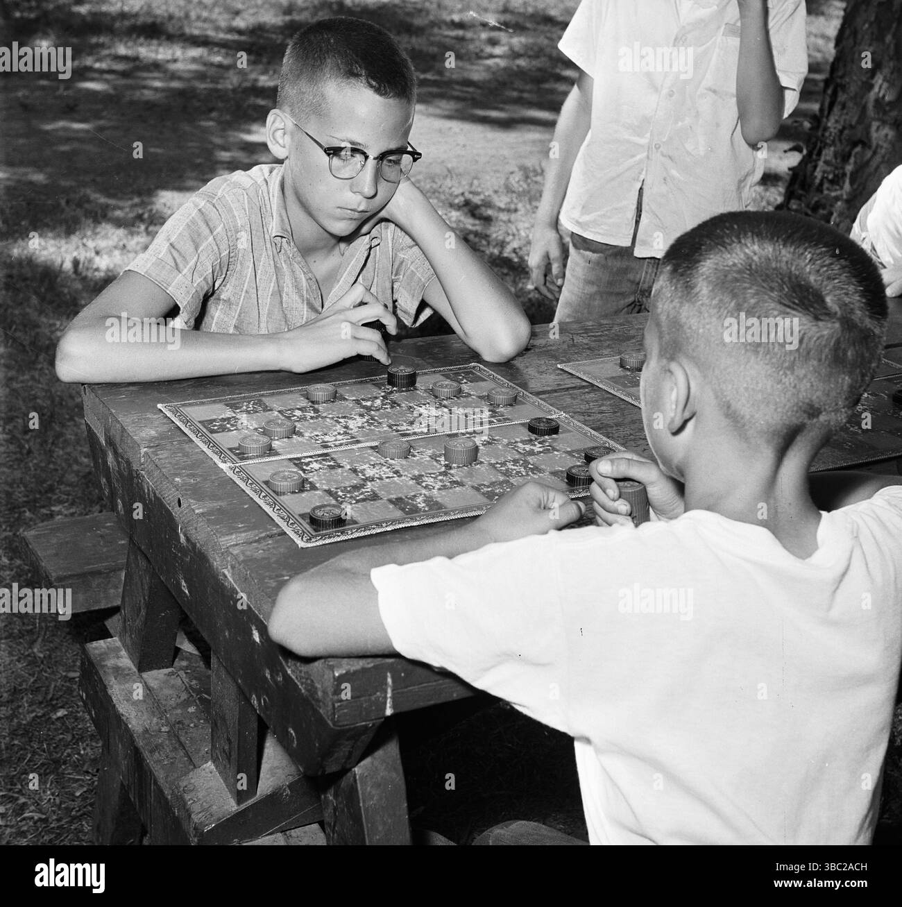 Zwei Jungs kämpfen auf einem Schachbrett, ca. 1960. Stockfoto