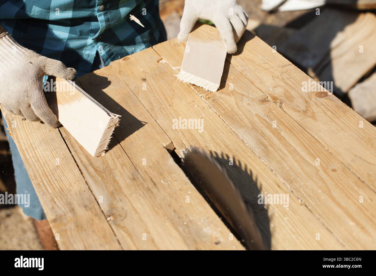 Hart arbeitender Holzarbeiter, der Holzbohlen schneidet, Fokus auf Säge Stockfoto