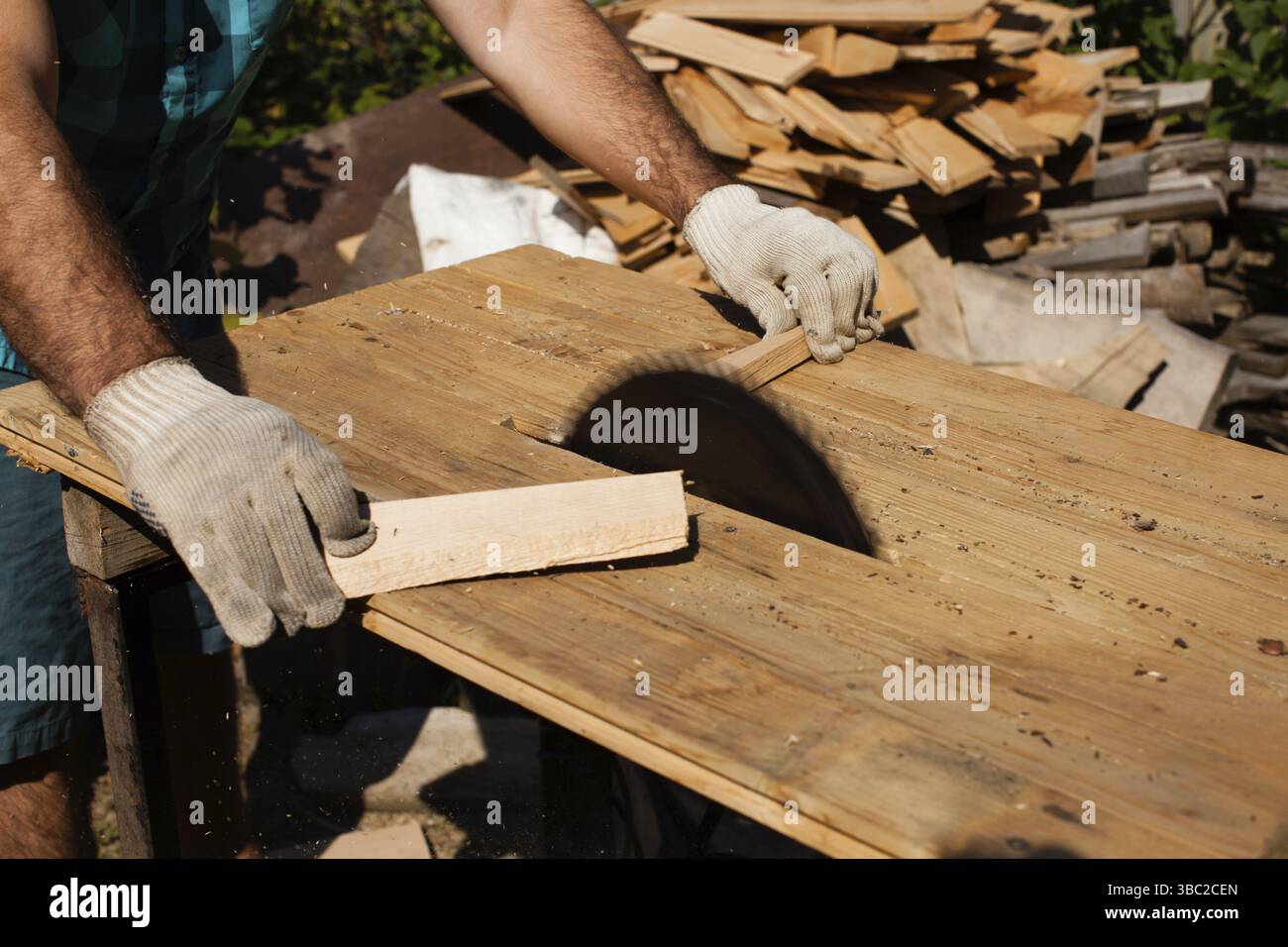 Hart arbeitender Holzarbeiter, der Holzbohlen schneidet, Fokus auf Säge Stockfoto