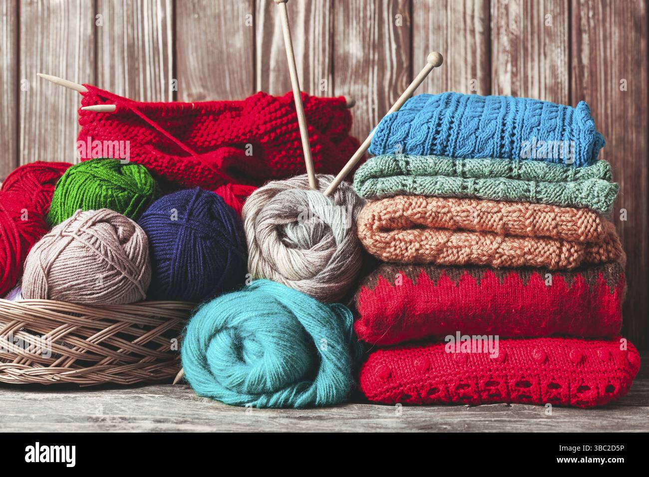 Farbfäden, Stricknadeln und Kleidung auf dem Holztisch Stockfoto