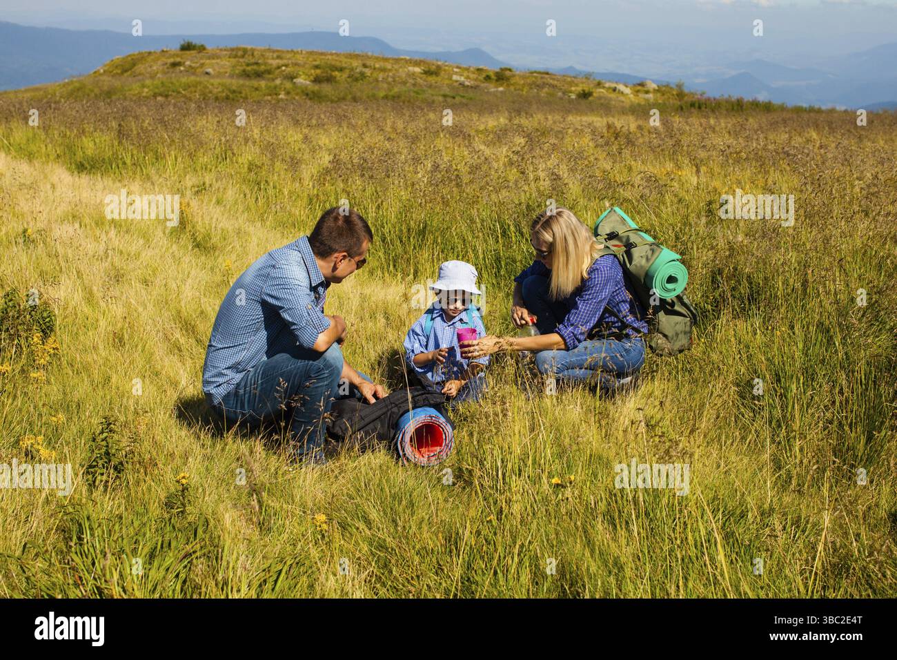 Die Familie von drei Personen, die in den Bergen unterwegs sind, Rest Stockfoto Die Familie von drei Personen, die in den Bergen unterwegs sind, Rest Stockfoto