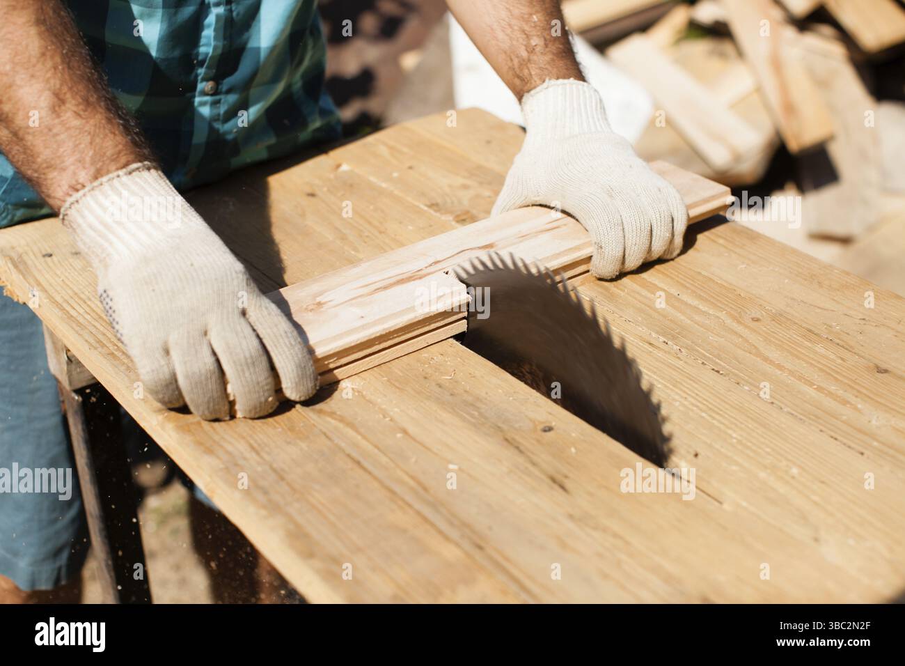 Hart arbeitender Holzarbeiter, der Holzbohlen schneidet, Fokus auf Säge Stockfoto