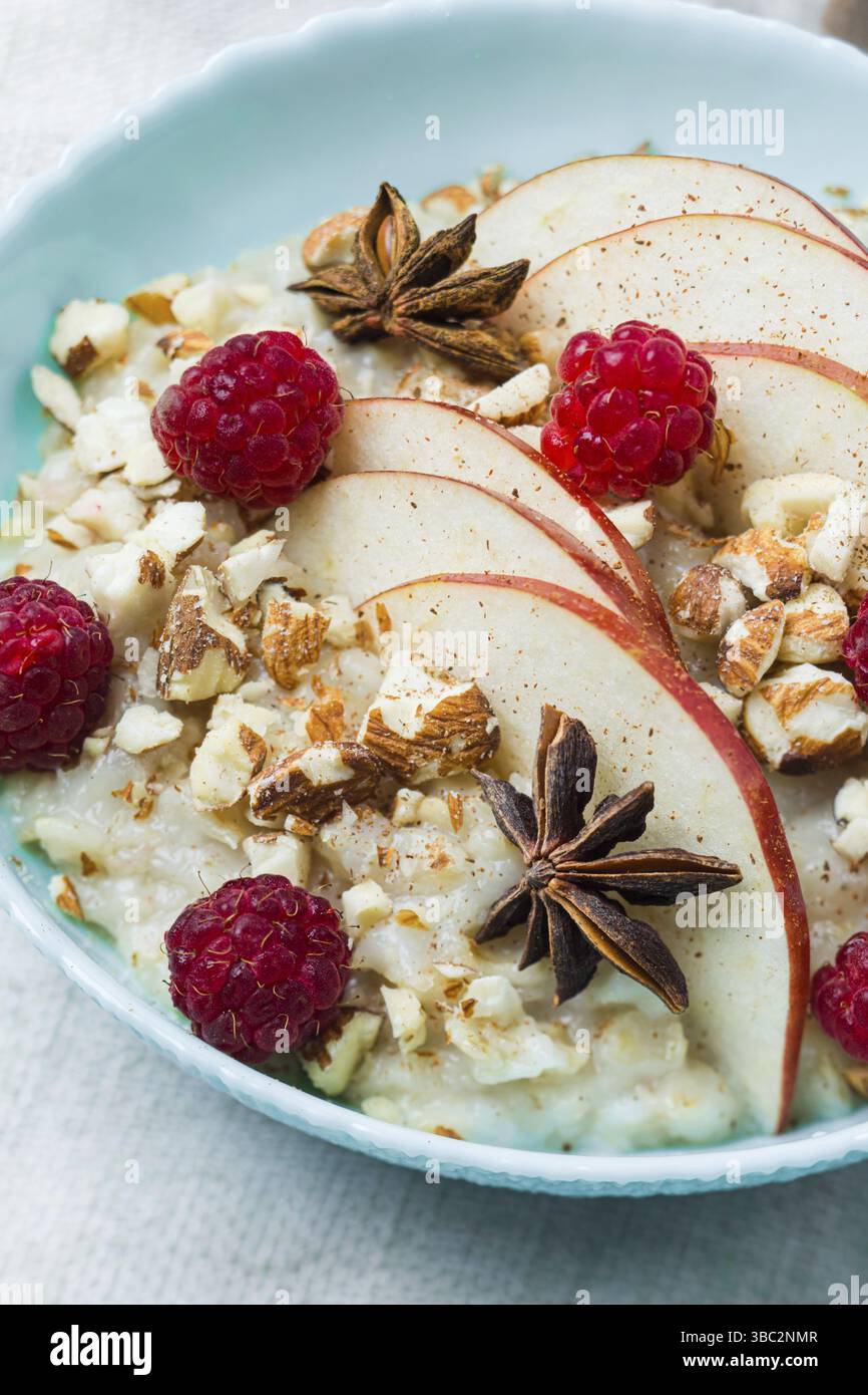 Einfache Alltagsgerichte können durch Zugabe zusätzlicher Zutaten für Kinder zubereitet werden. Frische Himbeeren und Apfelscheiben auf Haferbrei Stockfoto