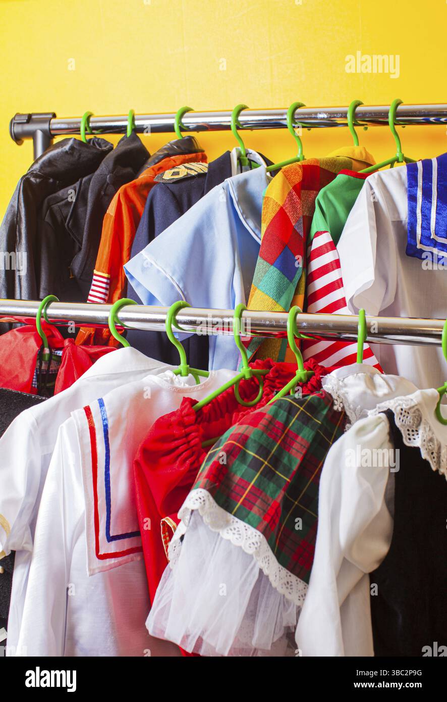 Regal mit vielen coolen Ferienkostümen für Kinder auf Kleiderbügeln im Kindermode-Showroom. Karnevalskostüme für Kinder. Mietservice im Stoffsho Stockfoto
